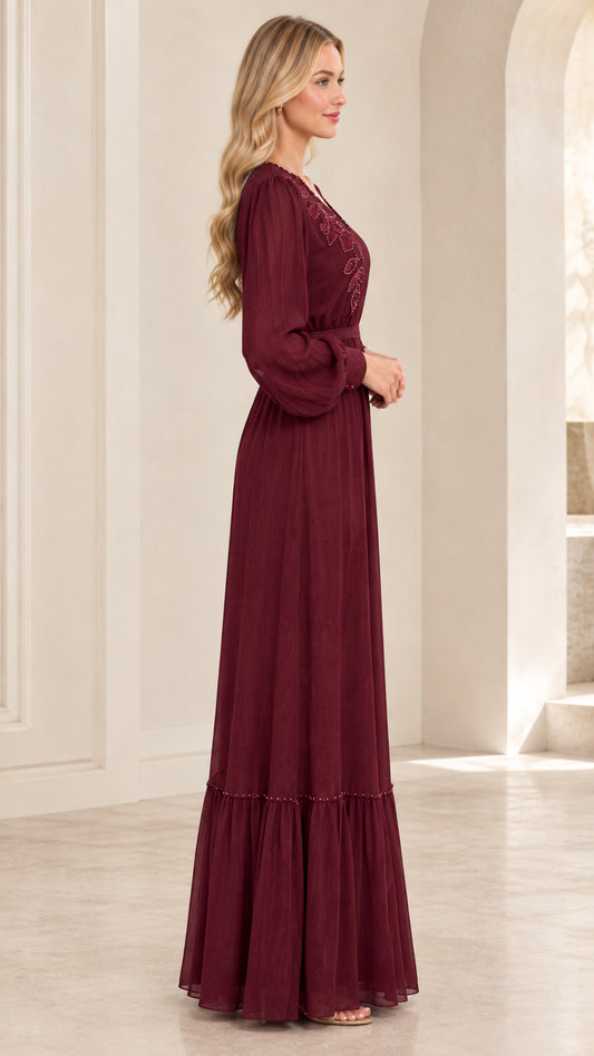 Side profile view of woman wearing burgundy floor-length long sleeve gown