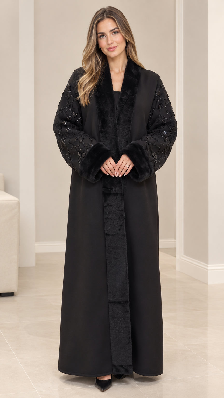 Front full-length view of model wearing black open-front abaya coat with faux fur collar and sequined sleeves