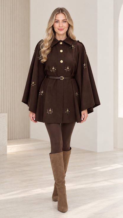Front view of woman wearing chocolate brown embellished belted cape coat with tall boots