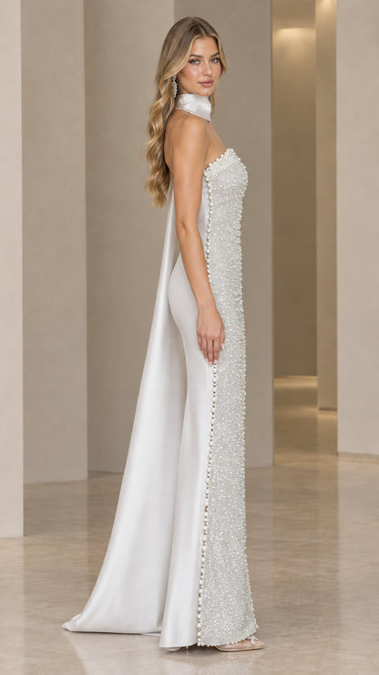 Side profile of silver beaded evening gown showcasing pearl trim and flowing cape
