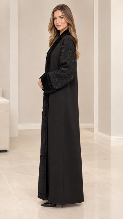 Side profile view of elegant black long coat with plush fur trim and embellished sleeves