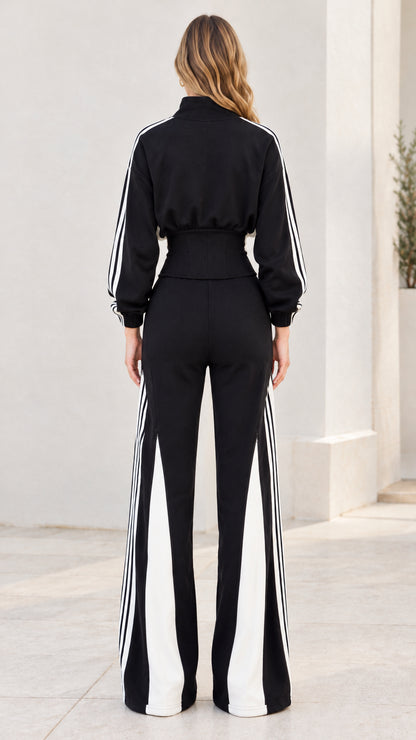 Back view of model wearing black zip jacket and wide-leg track pants