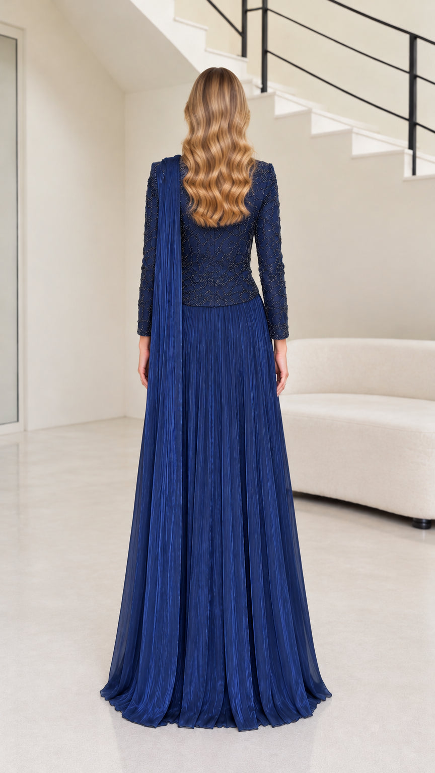 Back full-length view of navy blue pleated evening gown showing rear drape and high neckline