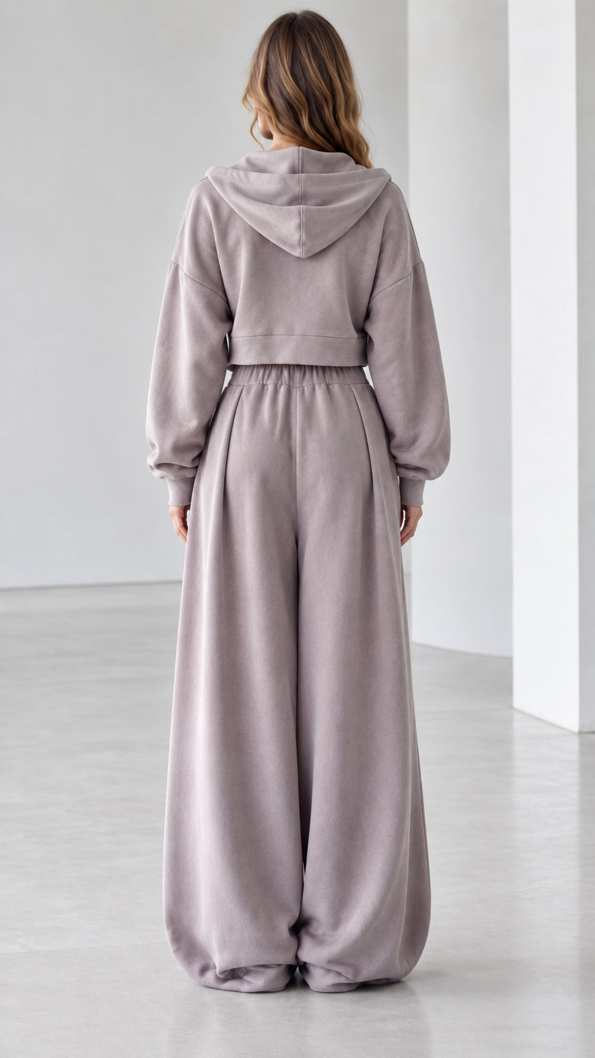 Back view of woman wearing mauve hooded sweatshirt and fluid wide-leg lounge pants