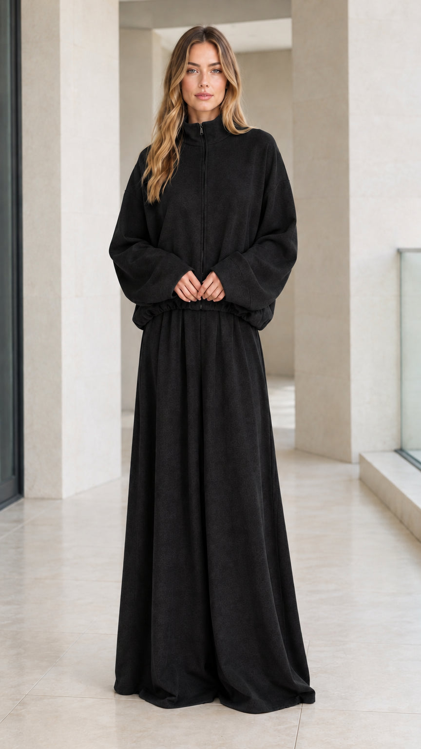 Front view of woman wearing solid black zip-up lounge jacket and matching wide-leg pants