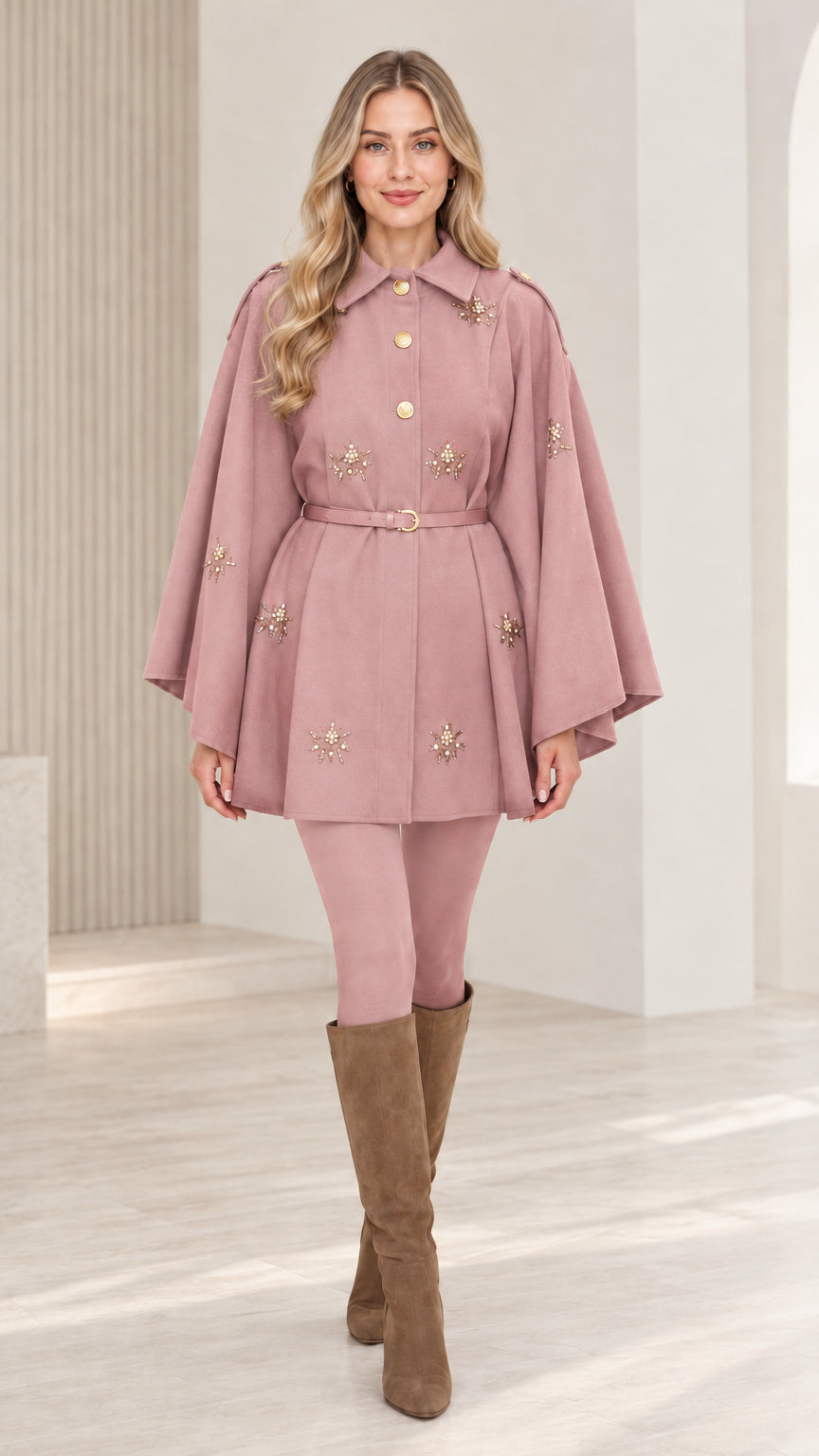 Front view of woman wearing dusty rose embellished button-front belted cape coat