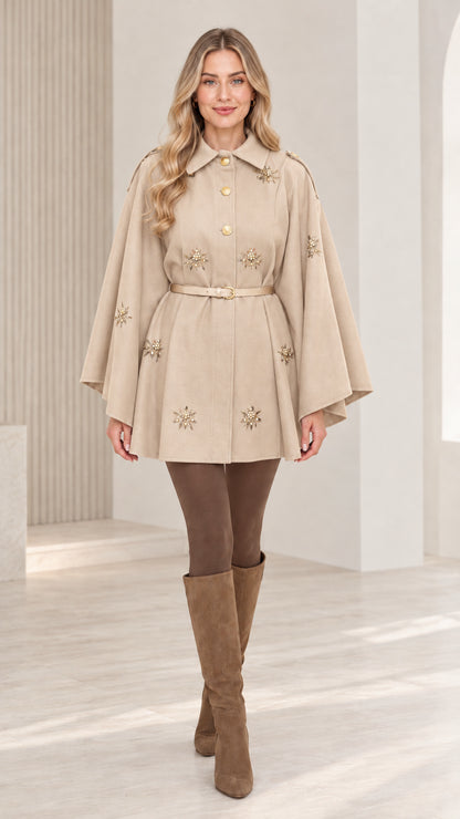 Front view of woman wearing beige embellished button-front belted cape coat